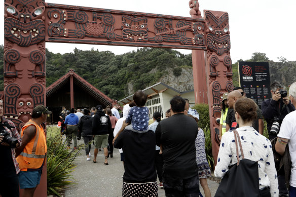 Families of victims of the White Island eruption walk into the marae.