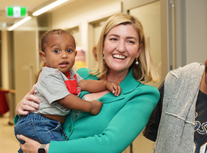 Health Minister Fentiman holds two-year-old Joseph, who came to QCH to visit his sister.