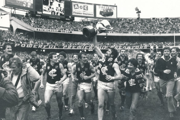 Peter Bosustow, premiership cup in hand and Carlton scarf flowing, leads the triumphant Blues on a victory lap of the MCG after the Grand Final.