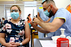 Nurse manager Sue McGrady receives the Pfizer vaccine at the Royal Prince Alfred Hospital Vaccination Hub in Sydney, Australia, Monday, Feb. 22, 2021. Australia has started its COVID-19 vaccination program days after its neighbor New Zealand with both governments deciding their pandemic experiences did not require regulation short cuts. (Toby Zerna/Pool Photo via AP)