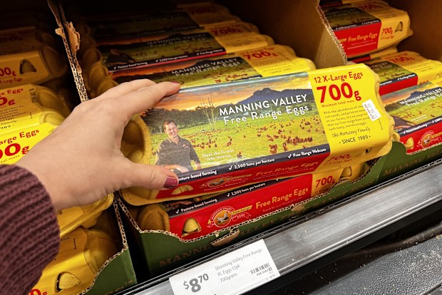 A shopper picking up a carton of eggs.