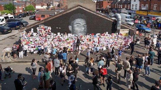Crowds gather at the newly repaired Marcus Rashford mural in Manchester.