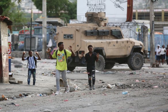 Youths raise their hands to show police they are not carrying weapons during an anti-gang operation at the Portail neighborhood in Port-au-Prince, Haiti.