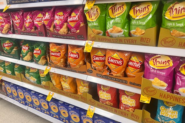 Packets of Smiths chips in various flavour in a supermarket on shelves.