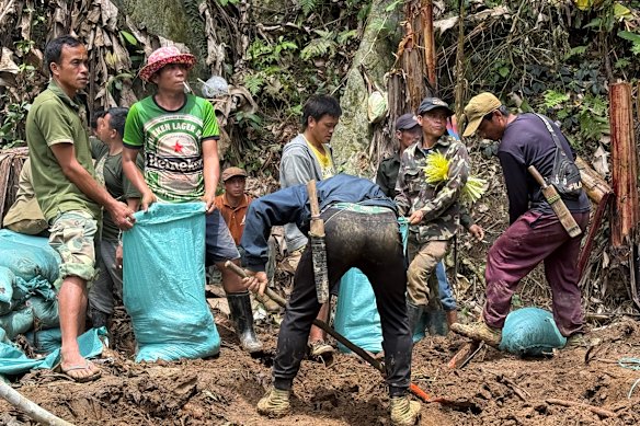 Workers and volunteers filling sandbags near the entrance of the flooded cave containing seven trapped villagers.