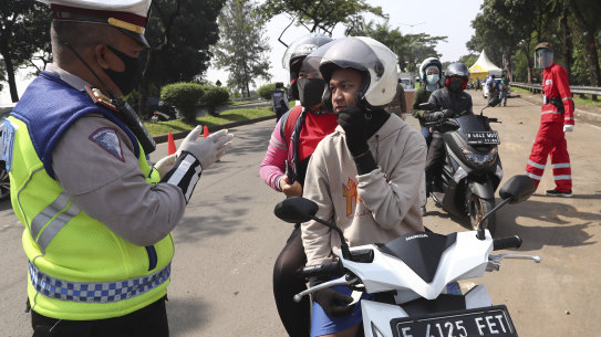 nA officer questions a motorist at a police check point during the imposition of large-scale restriction to curb the spread of the new coronavirus outbreak in Tangerang, Indonesia.