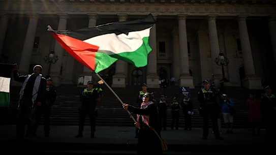 A pro-Palestine protester waves a flag outside Parliament House in the CBD.