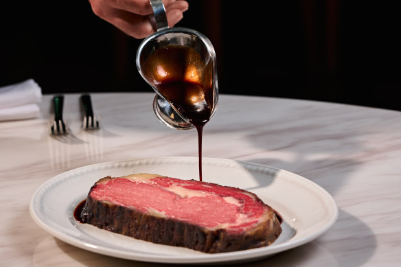 A red wine sauce with a glossy car showroom finish is poured around prime rib at the table.