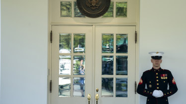 A marine is posted outside the West Wing of the White House, which means the President is in the Oval Office.