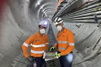 Acting Cross River Rail project director Tai Luong and Graeme Newton look at drawings as the tube to Woolloongabba stretches behind them.
