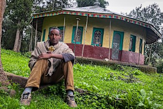 Priest Yared Adamu holds an Ethiopian Orthodox cross in the churchyard where residents say more than 50 civilians have been laid to rest in makeshift graves.