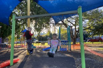 Monica Mrsic and her brother swing in a Brisbane park under shade cloth. Brisbane City Council will provide shade over every Brisbane playground over the next three years.