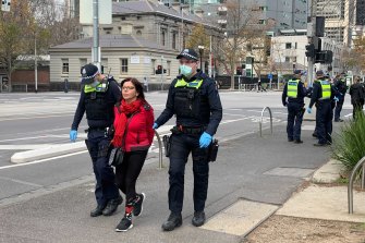 A woman is led away by Victoria Police during an anti-lockdown protest on Saturday.