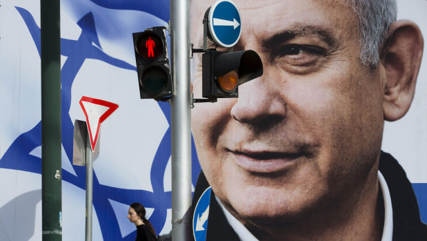 A woman walks by an election campaign billboard showing Israel's Prime Minister Benjamin Netanyahu, the Likud party leader, in Tel Aviv, Israel, on Thursday, March 28.