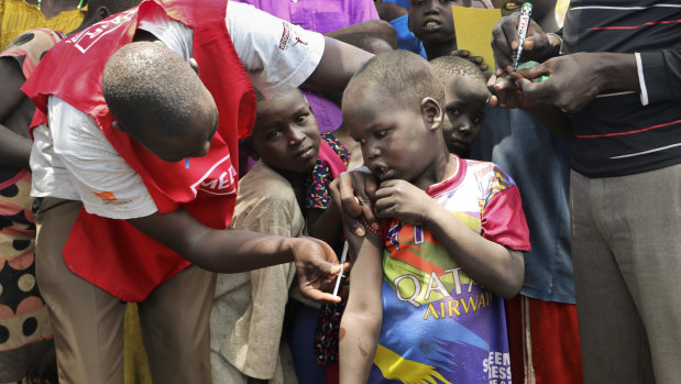 A community health worker vaccinates children against measles outside of Kuajok, South Sudan.