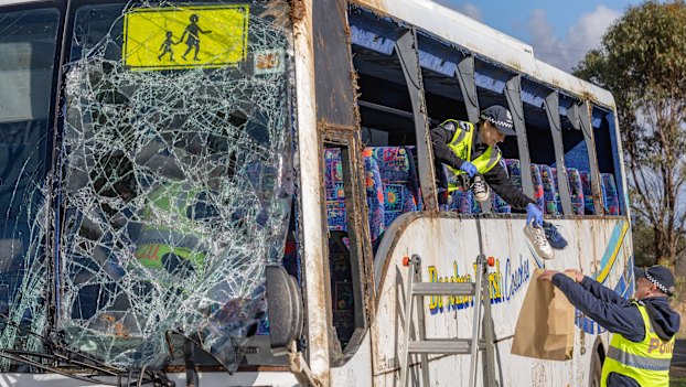 Police remove children’s shoes and belongings from the wreckage after the bus was righted the following day.