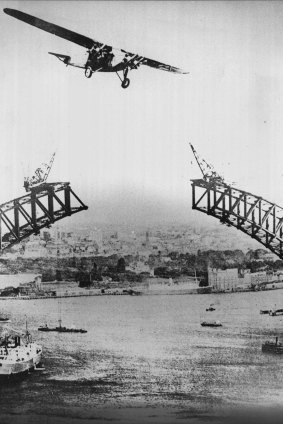 The Southern Cloud flies over an uncompleted Sydney Harbour Bridge.