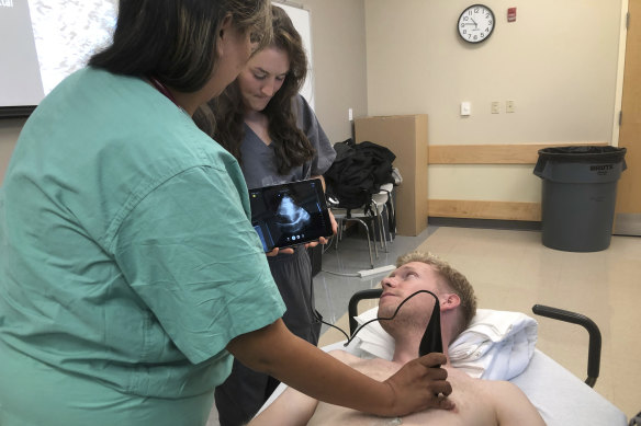 Students practise on each other using a Butterfly iQ handheld ultrasound device attached to a tablet during a class at Indiana University medical school.