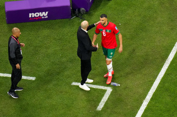 Romain Saiss is embraced by Morocco coach Walid Regragui.