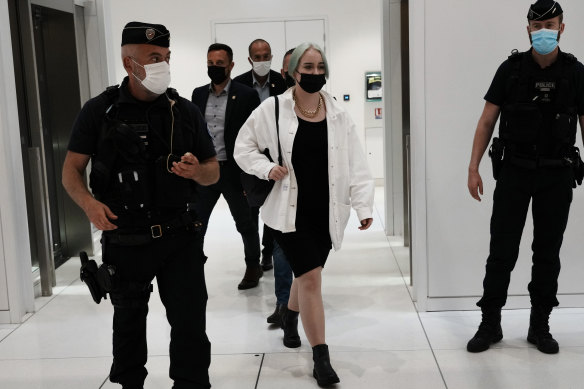 The teenager identified by her first name, Mila, leaves the courtroom in Paris. Thirteen others are charged with threatening her.