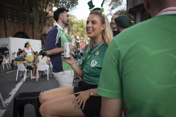 Jess Johnston and partner Ollie Fleetham (background) enjoy St Patrick’s Day at the Rocks under the shadow of the Harbour Bridge in stiflingly hot conditions.