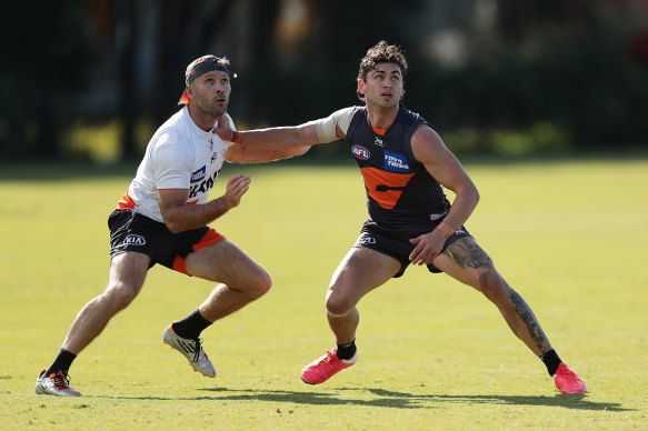 Tim Taranto holds off GWS assistant coach Mark McVeigh in a training drill.