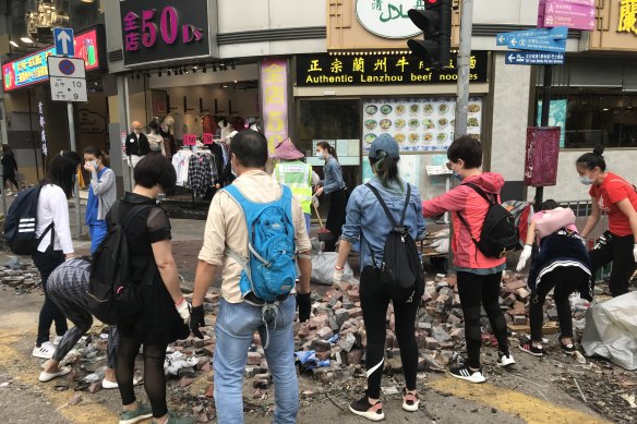 Hong Kong residents including May, 39, volunteer to clean up brick after clashes between protesters and police.