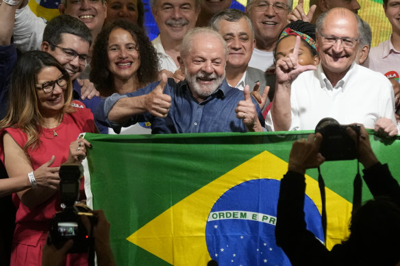 Luiz Inacio Lula da Silva (blue shirt) celebrates with wife Rosangela Silva and running mate Geraldo Alckmin.