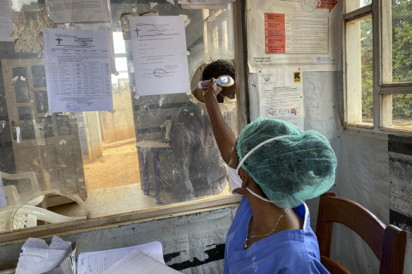 A medical worker checks a person’s temperature at the Matanda Hospital in Butembo, during the outbreak of Ebola in the DR of Congo, 