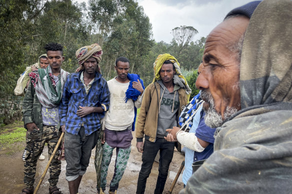 Men gather to speak to injured militia fighter Kibret Bidere, second from right with bandaged arm, after he joined locals to try to fend off Tigrayan soldiers. 