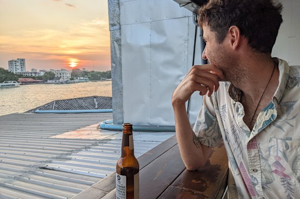 The writer drinks beer at sunset on the river.