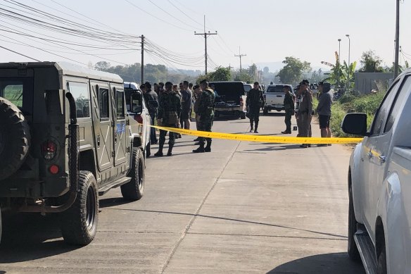 Thai police and soldiers watch as a forensics team examine the body of an alleged drug runner.