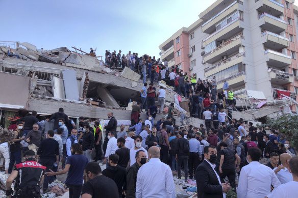 Rescue workers and residents try to rescue people trapped in a collapsed building in Izmir, Turkey, immediately after the earthquake struck.