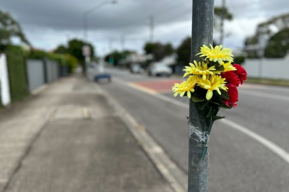 Flowers remain affixed to the pole where the ghost bike was previously left.
