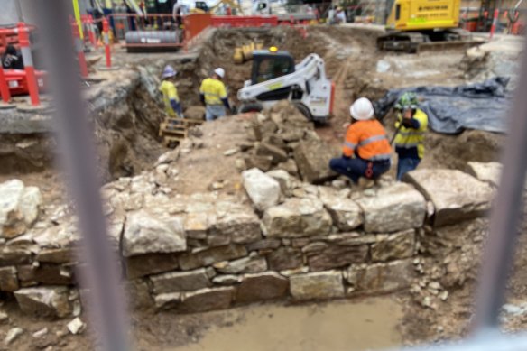 A bulldozer breaking up and removing the significant archaeological remains under Adelaide Street.