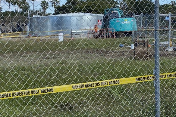 Tape warns “Danger asbestos dust hazard” at the site, which used to be a military facility.