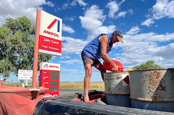A farmer in Queensland tops up fuel barrels.