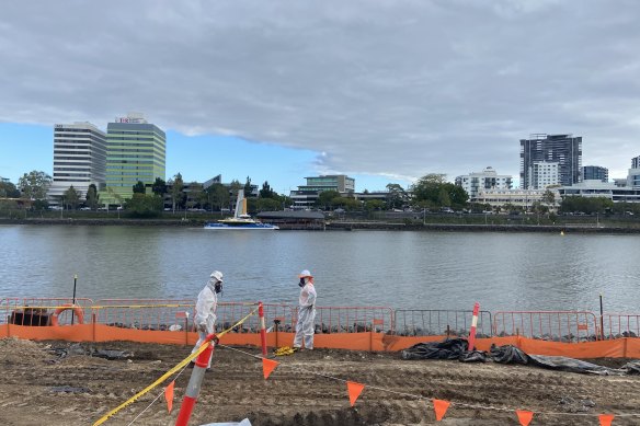 Contaminated soil workers in HAZCHEM gear cap contaminated coal tar and asbestos from flowing into the Brisbane River. 