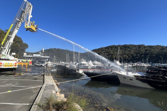 NSW Fire and Rescue work to extinguish the three boats that caught fire in Church Point.