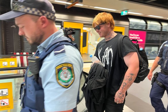 Police escort a man out of North Sydney station on Friday afternoon.