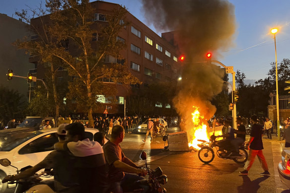A police motorcycle and a trash bin burn during a protest over the death of Mahsa Amini in downtown Tehran, Iran. 