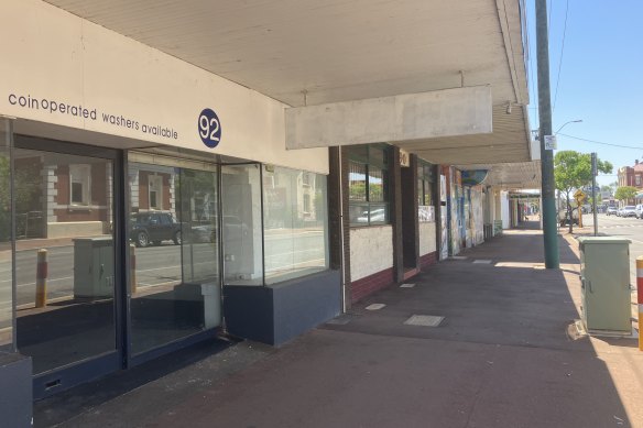 Shops and houses are boarded up and empty.