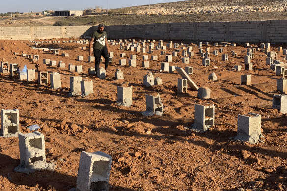 A man walks by the graves of the flash flood victims in Derna, Libya.