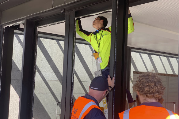 Workers inspect the smashed front doors of the New Zealand Parliament on Wednesday.