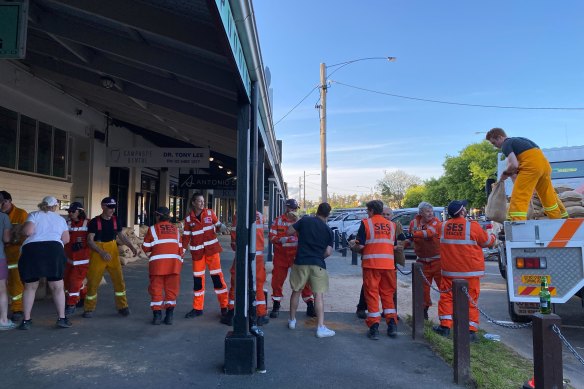 SES and CFA volunteers form a human chain as they help lay sandbags at The Black Pudding Cafe.