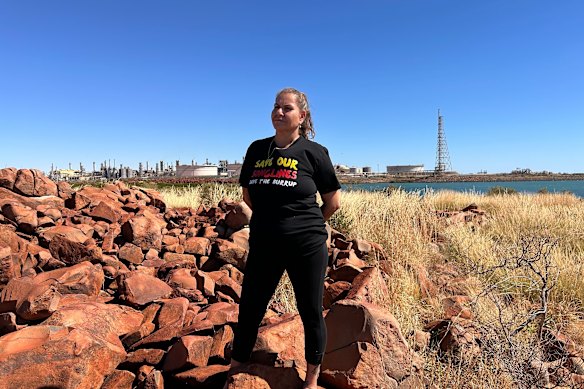 Murujuga custodian Raelene Cooper standing on Murujuga, with Woodside’s Karratha plant in the background.