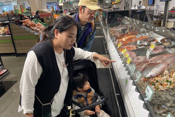 Naoka and Sanshiro Miro look carefully at seafood labels identifying where the fish and prawns they wish to buy are from.  Restaurants and cafes are not required to identify where their fish comes from.