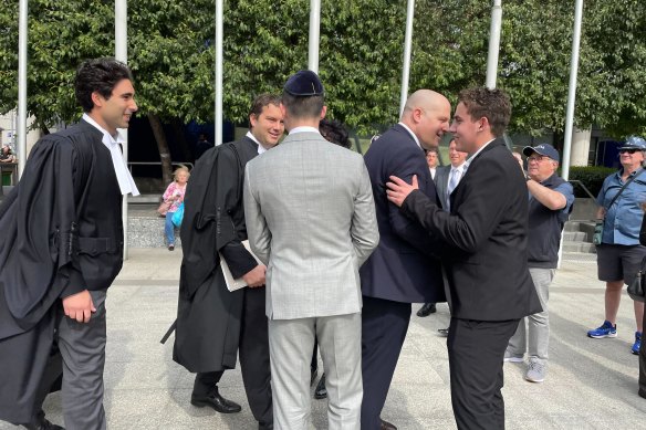 Former Brighton Secondary College students Matt Kaplan (right) and Liam Arnold-Levy (centre) celebrate with their legal team, who largely worked pro bono, outside court.