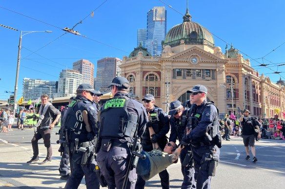 Police remove an Extinction Rebellion protester after a sit-in outside Flinders Street Station on Saturday afternoon.