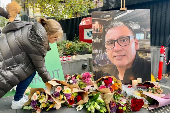 A woman leaves flowers at a vigil for Rob Karkut in May 2023.